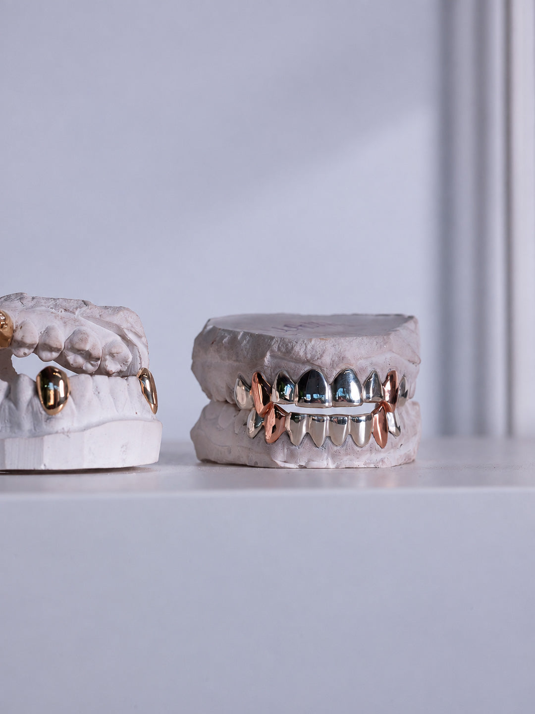 Fang grillz on dental moulds, an 18k yellow gold set and a white gold set with rose gold fang canines