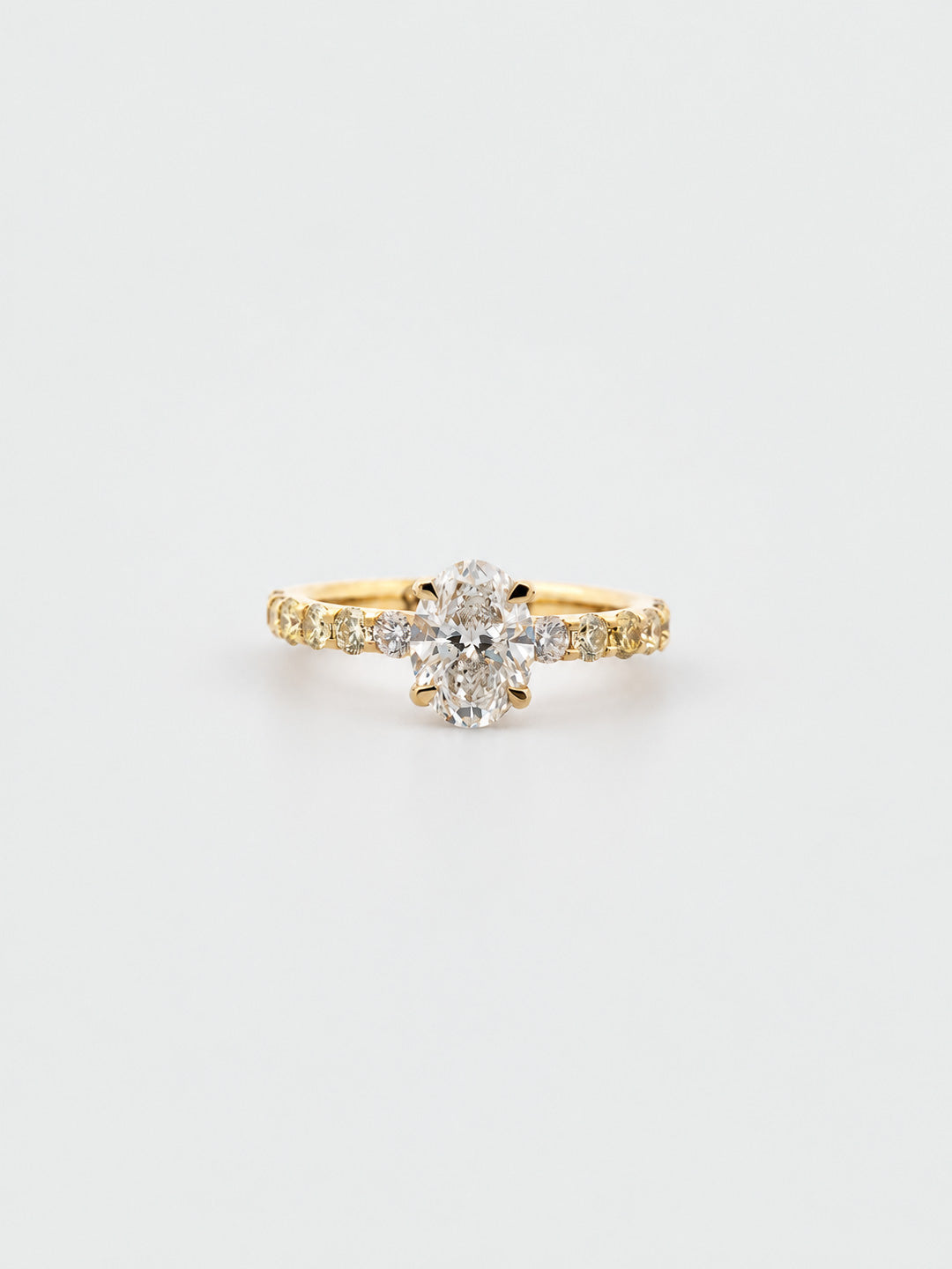 Custom engagement ring in yellow gold with oval diamond solitaire and pavé shoulders, bespoke by Illoom Sydney