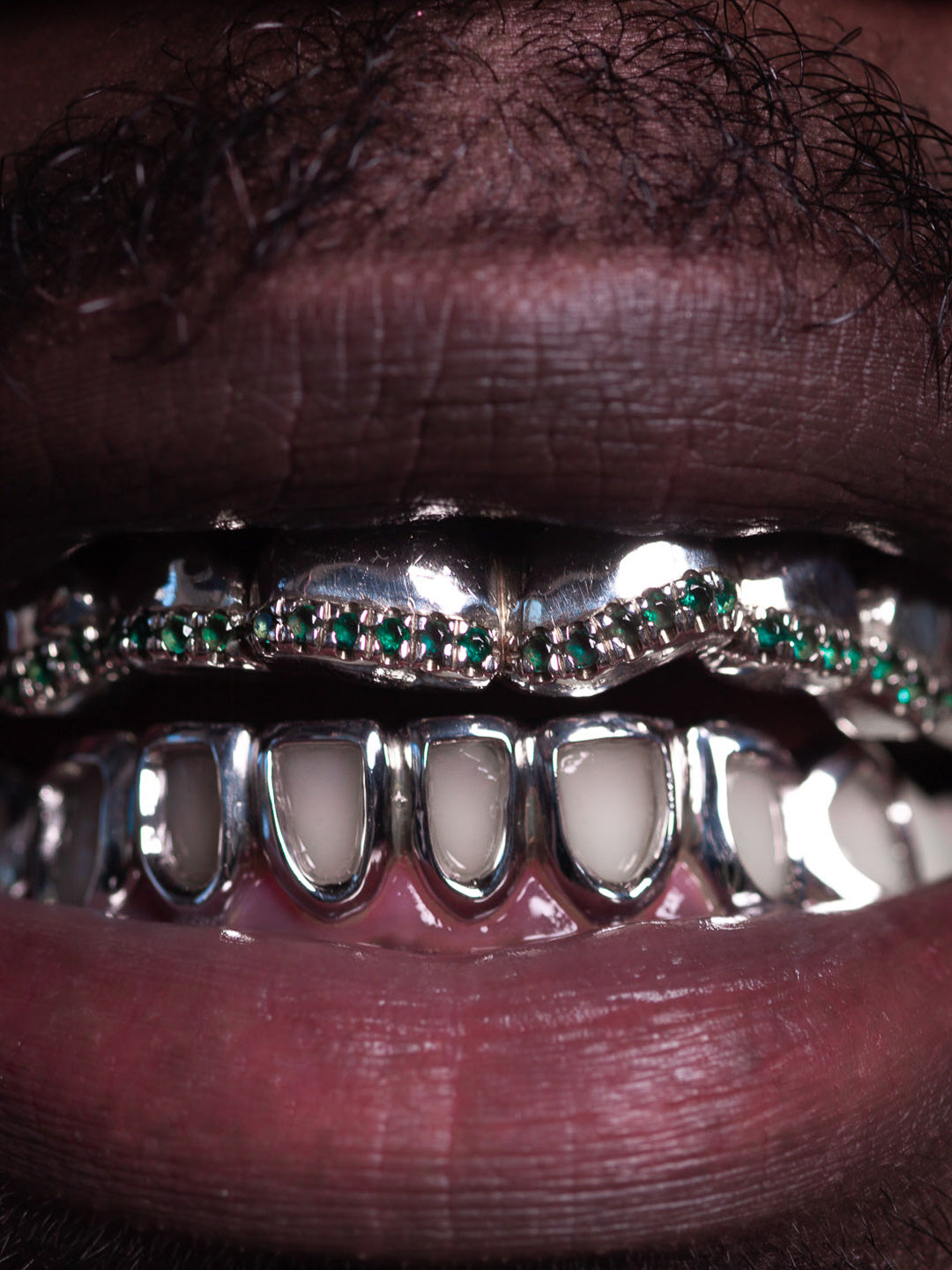 White gold grillz worn with emerald tipped top row and classic window bottom row