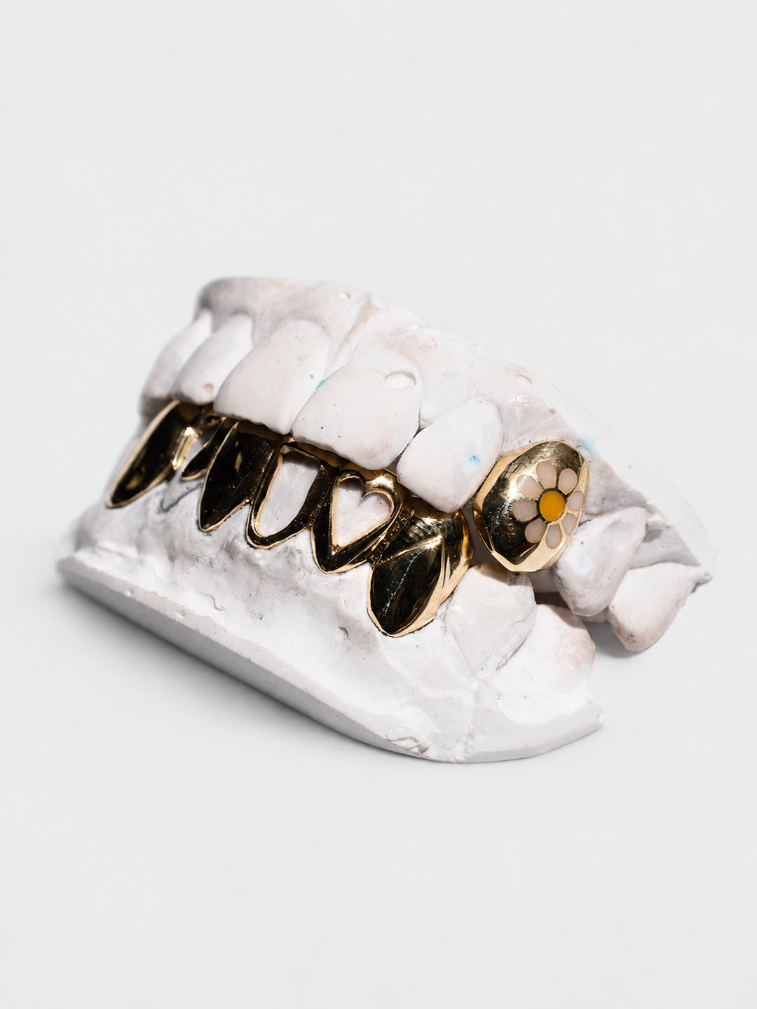 Heart window grillz in 18k yellow gold across the bottom six with a daisy enamel top tooth, bespoke by Illoom Sydney