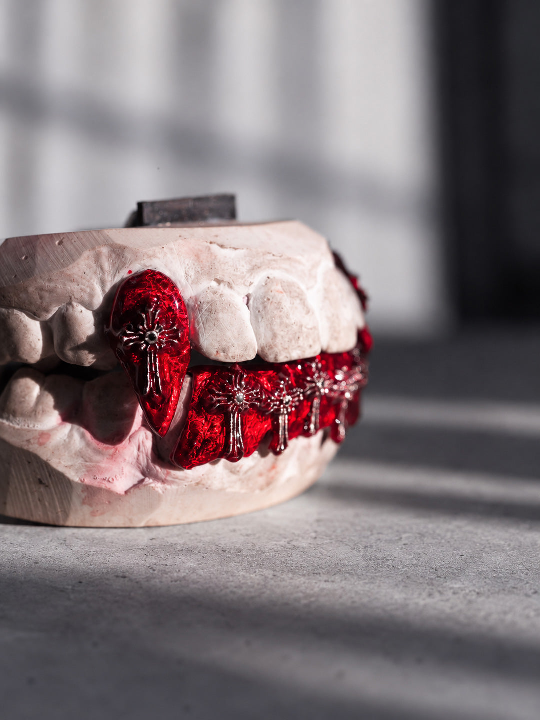Red enamel grillz with cross detailing across the bottom row and two top fangs, custom design on mould