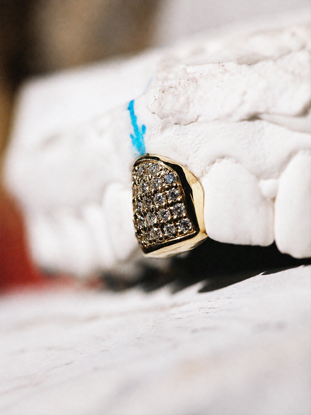 Single tooth grillz in 9k yellow gold, pavé set with natural diamonds, side profile on dental mould