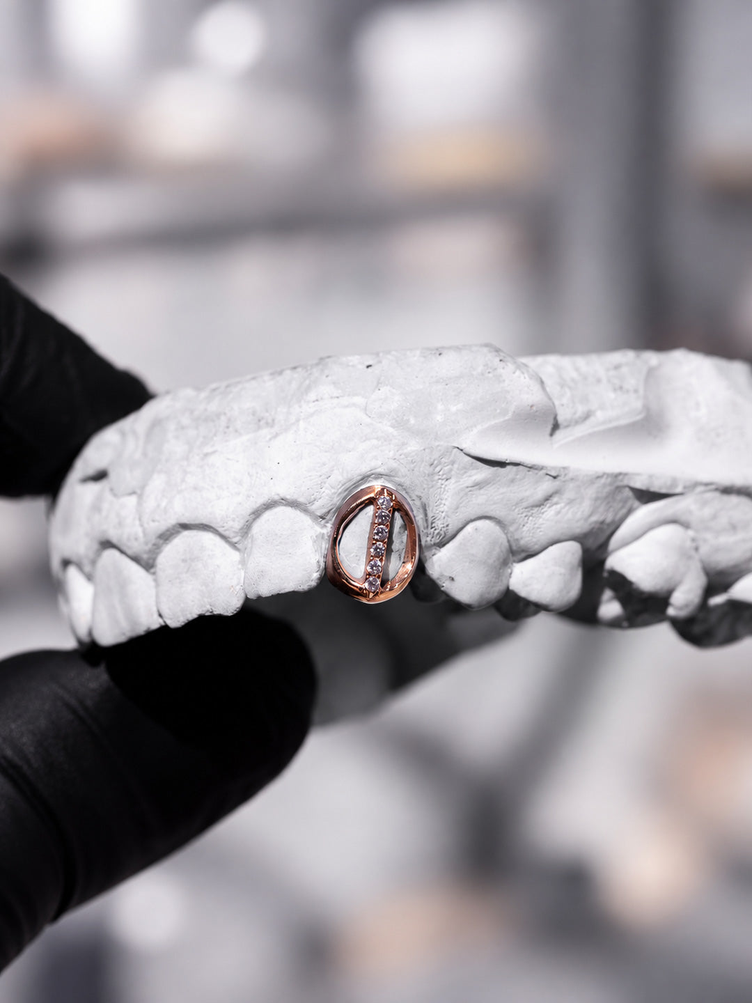 Single tooth diamond window grillz in rose gold with pavé white diamonds, profile view on dental mould