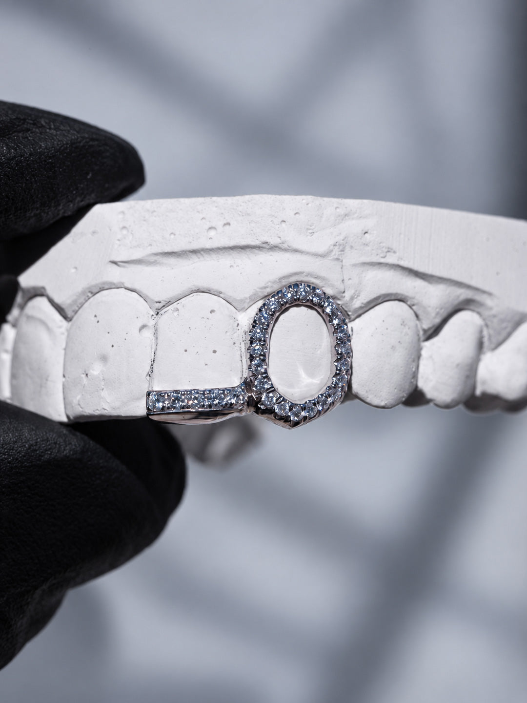Window grillz in silver with a pavé diamond row on the adjacent tooth, shown on dental mould